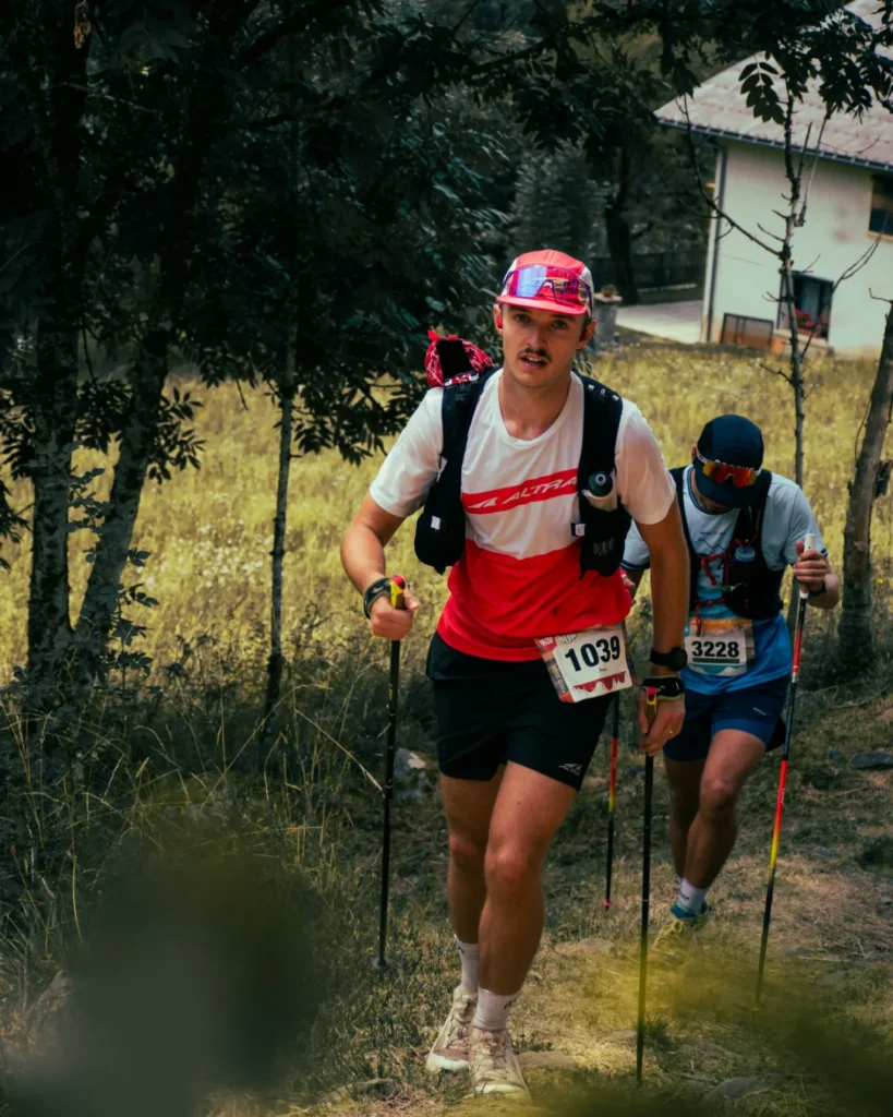 Zwei Trailrunner mit Stöcken und Trailrunning-Westen im Anstieg während eines Rennens