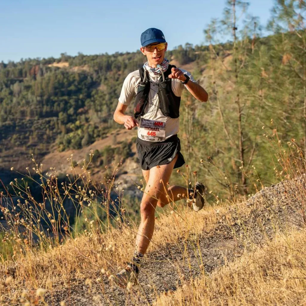 Trailrunner im Downhill auf einem Bergpfad mit eng anliegender Trailrunning-Weste
