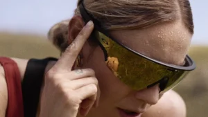 Triathlete wearing Oakley Meta Vanguard glasses with a gold Prizm lens, hand on the temple during an outdoor workout