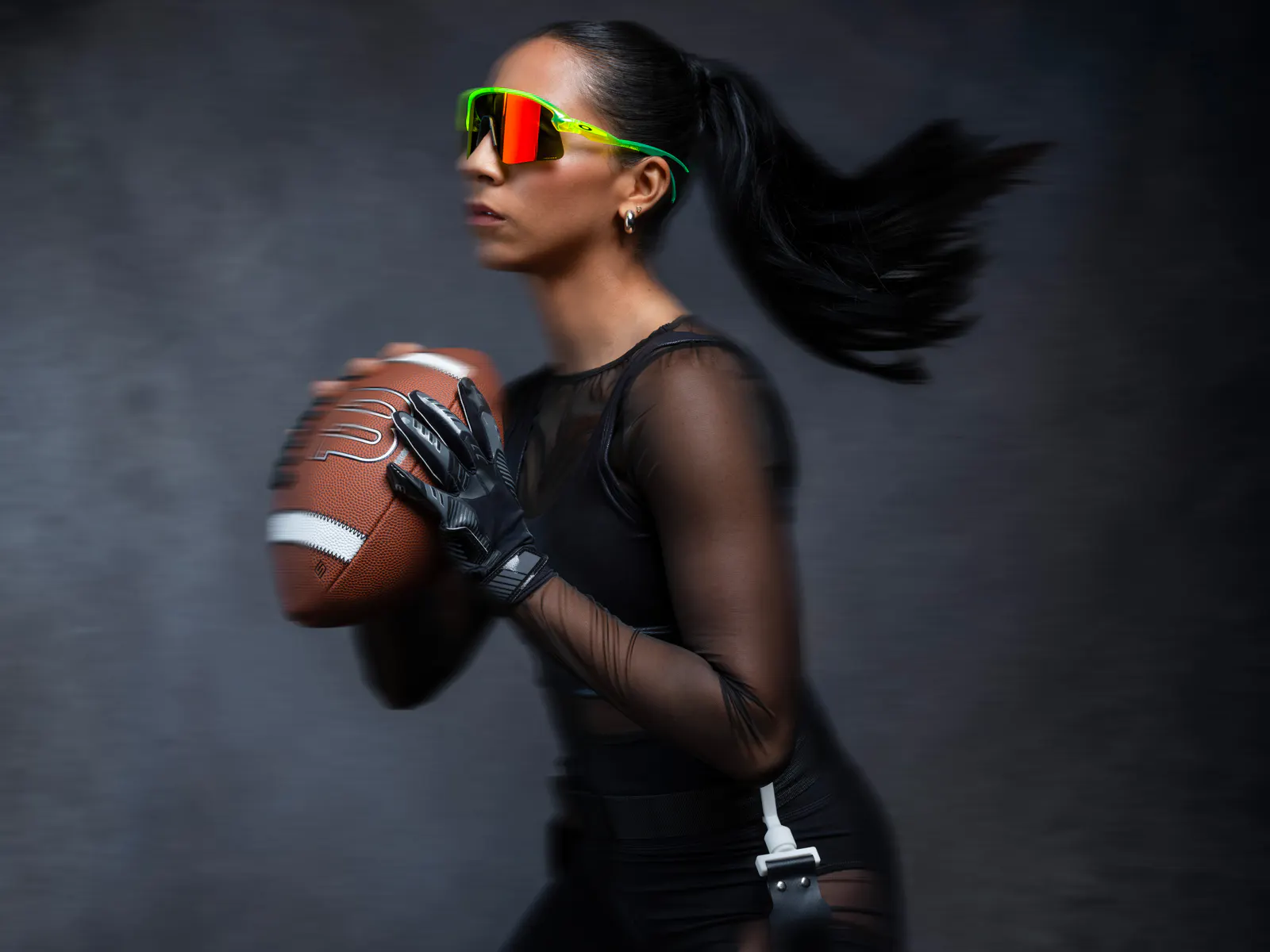 Atleta con occhiali Oakley Stunt Devil e lente Prizm, in movimento con un pallone da football