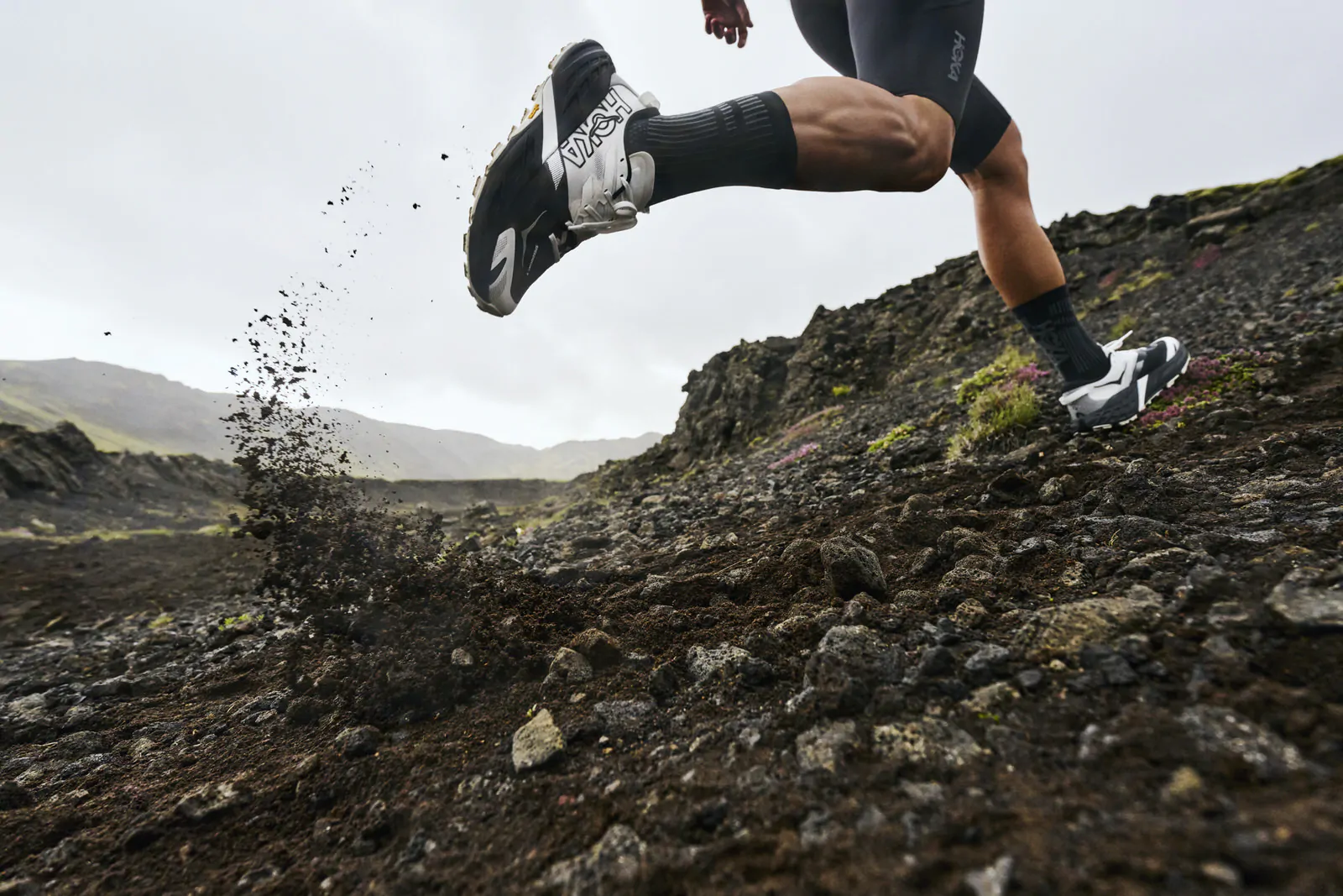 Hoka Speedgoat 7 en sendero técnico — vista lateral de la zapatilla de trail running con suela Vibram Megagrip